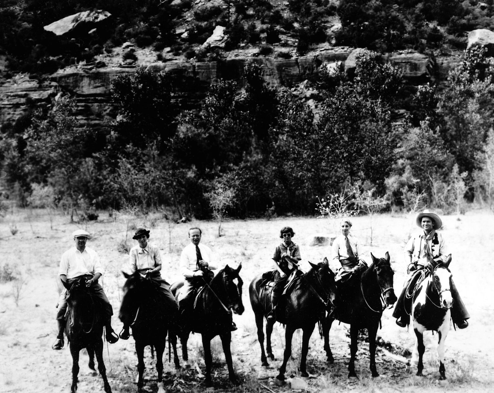Party of men and women on horseback in meadow in Zion Canyon.