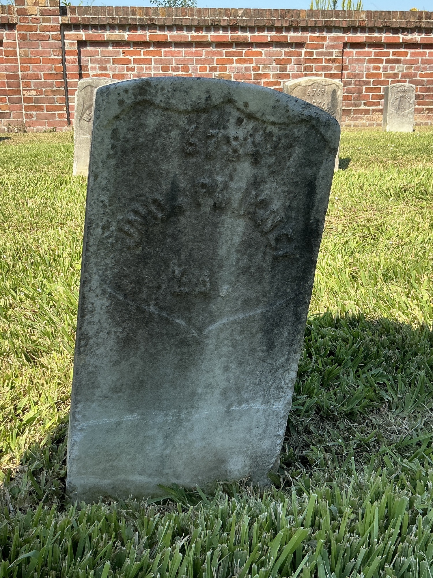 Front of historic upright marble headstone with recessed shield face.