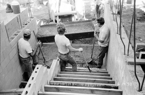 Workers taking a break from laying concrete during construction of headquarters addition.