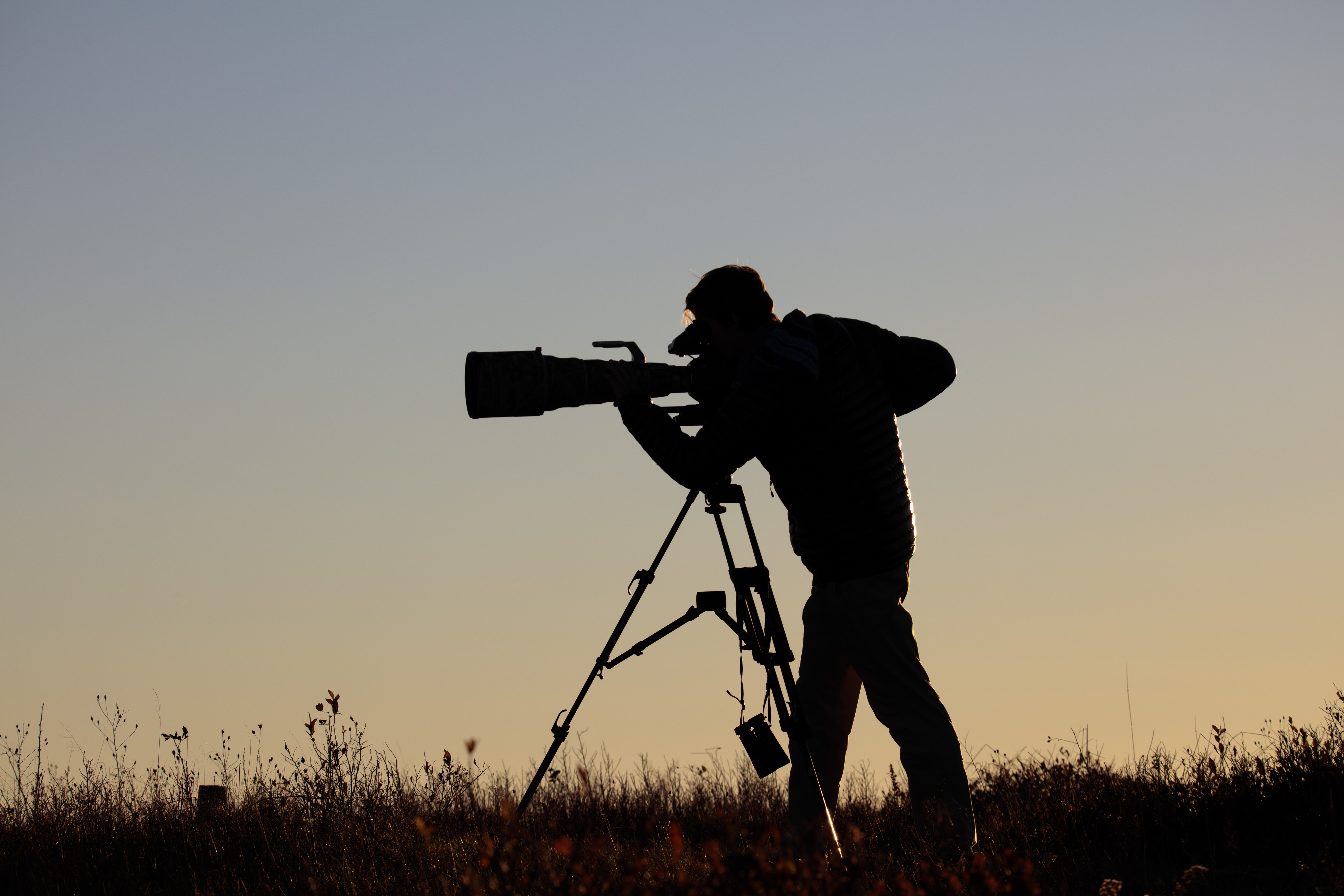 A silhouette of a videographer with a big lens