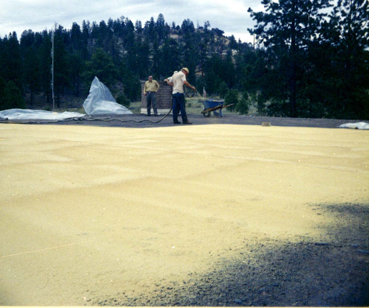 Two men watching as third man sprays foam sealant during reroofing project. Bryce Canyon National Park.