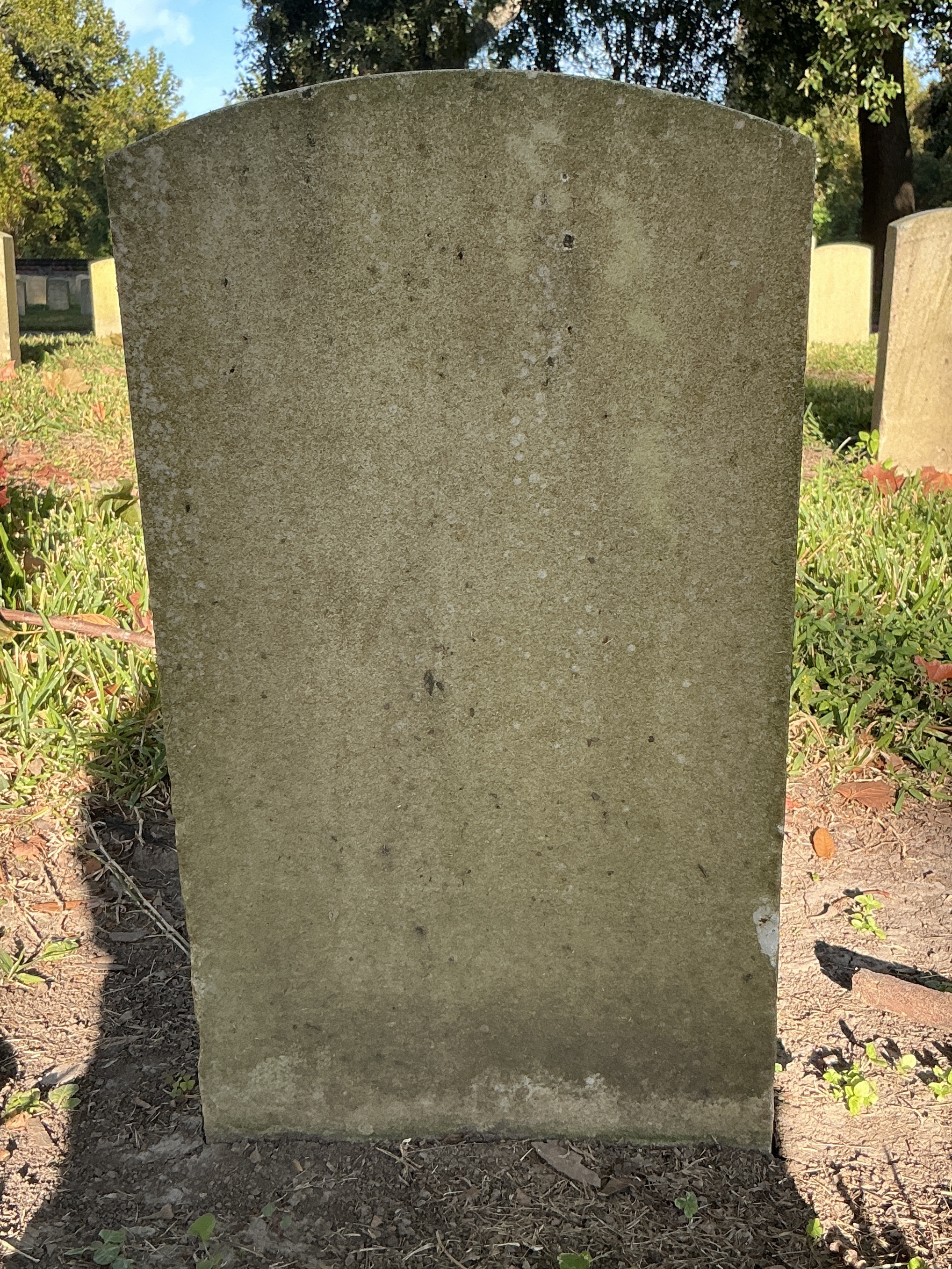 Back of historic upright marble headstone with recessed shield face.