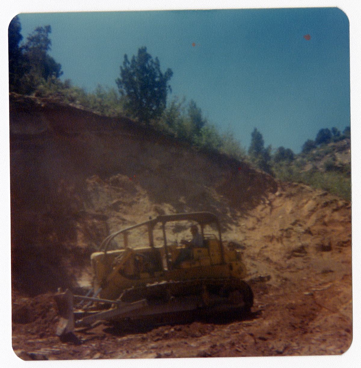 Man operating excavator to clear road during road work/repair in Kolob Canyon.