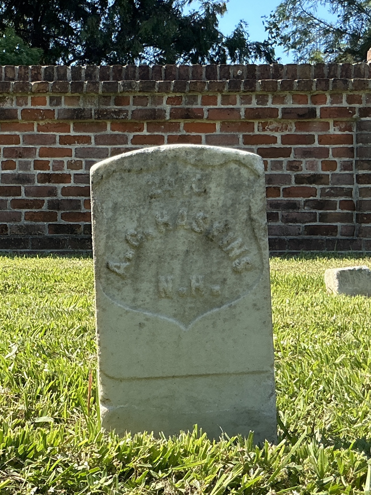 Front of historic upright marble headstone with recessed shield face.