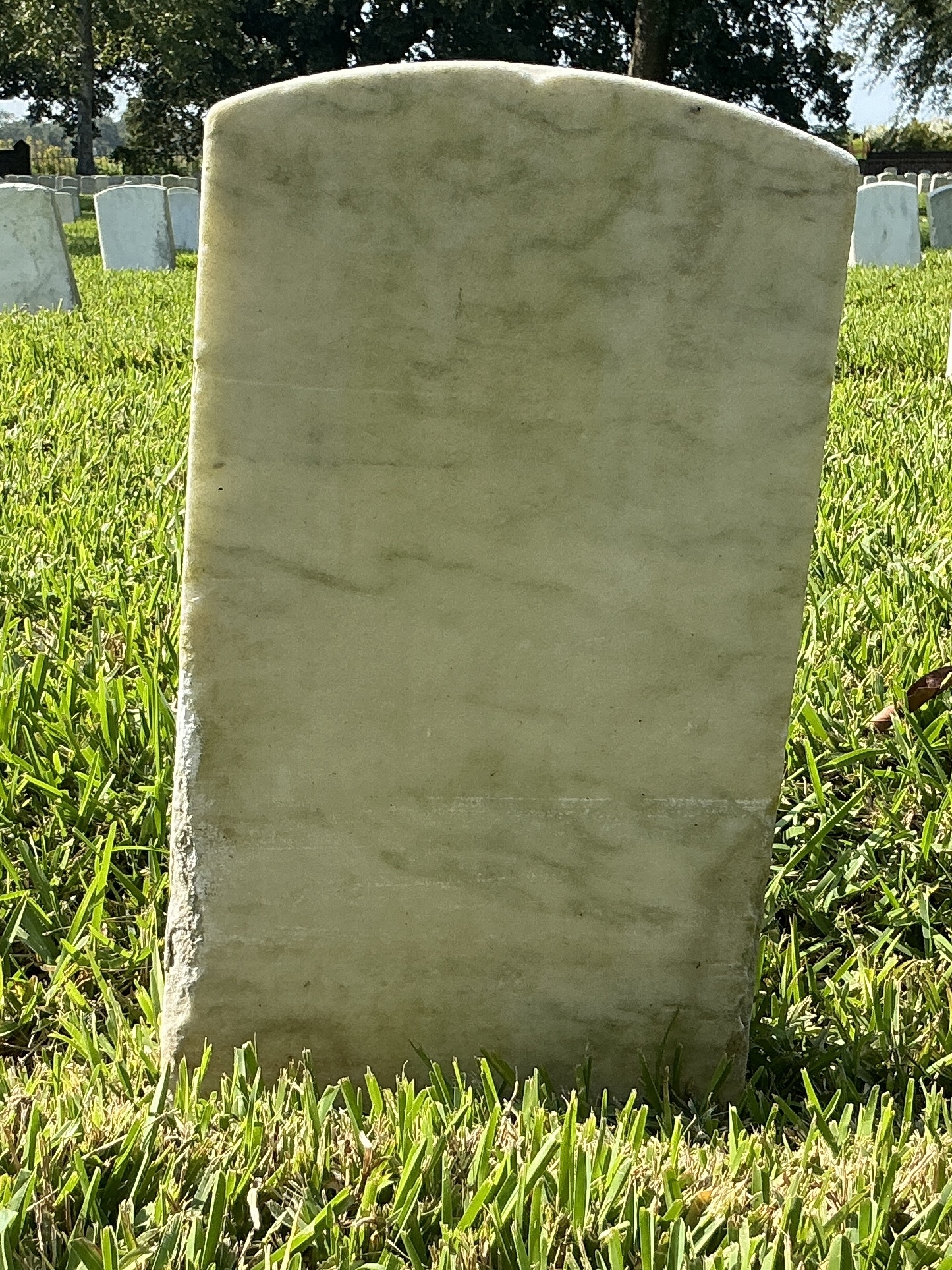 Back of historic upright marble headstone with recessed shield with recessed lettering face.