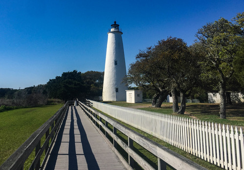 White lighthouse at the end of a boardwalk