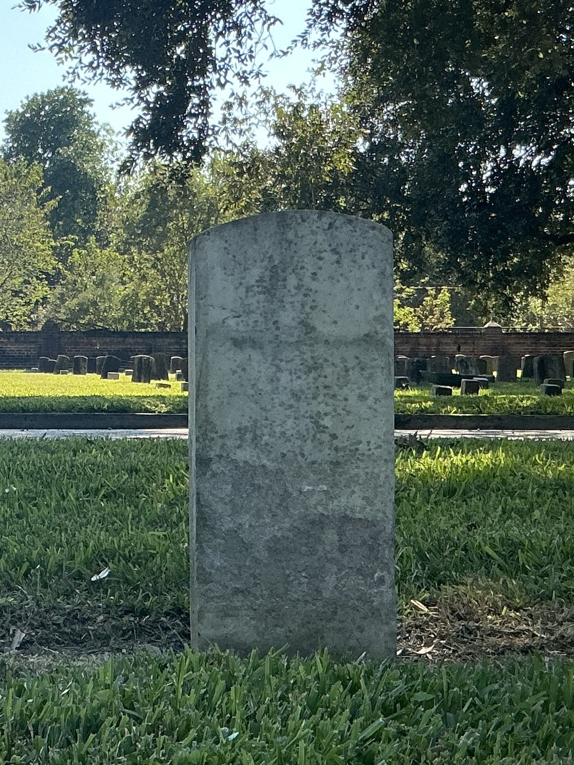 Back of historic upright marble headstone with recessed shield face.
