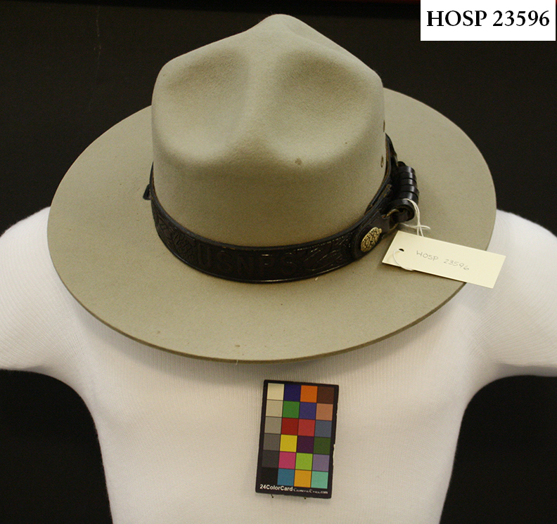 1 felt flat-brimmed National Park Service uniform hat. Greenish tan in color. Worn as part of winter uniform. Leather sweatband, leather hat band with traditional sequoia pinecones and brass accents. Sweat staining on sweatband, spots on exterior. 6 side vents, 2 grommets for head strap.
Belonged to Josie Fernandez, superintendent from 2004 - 2018.