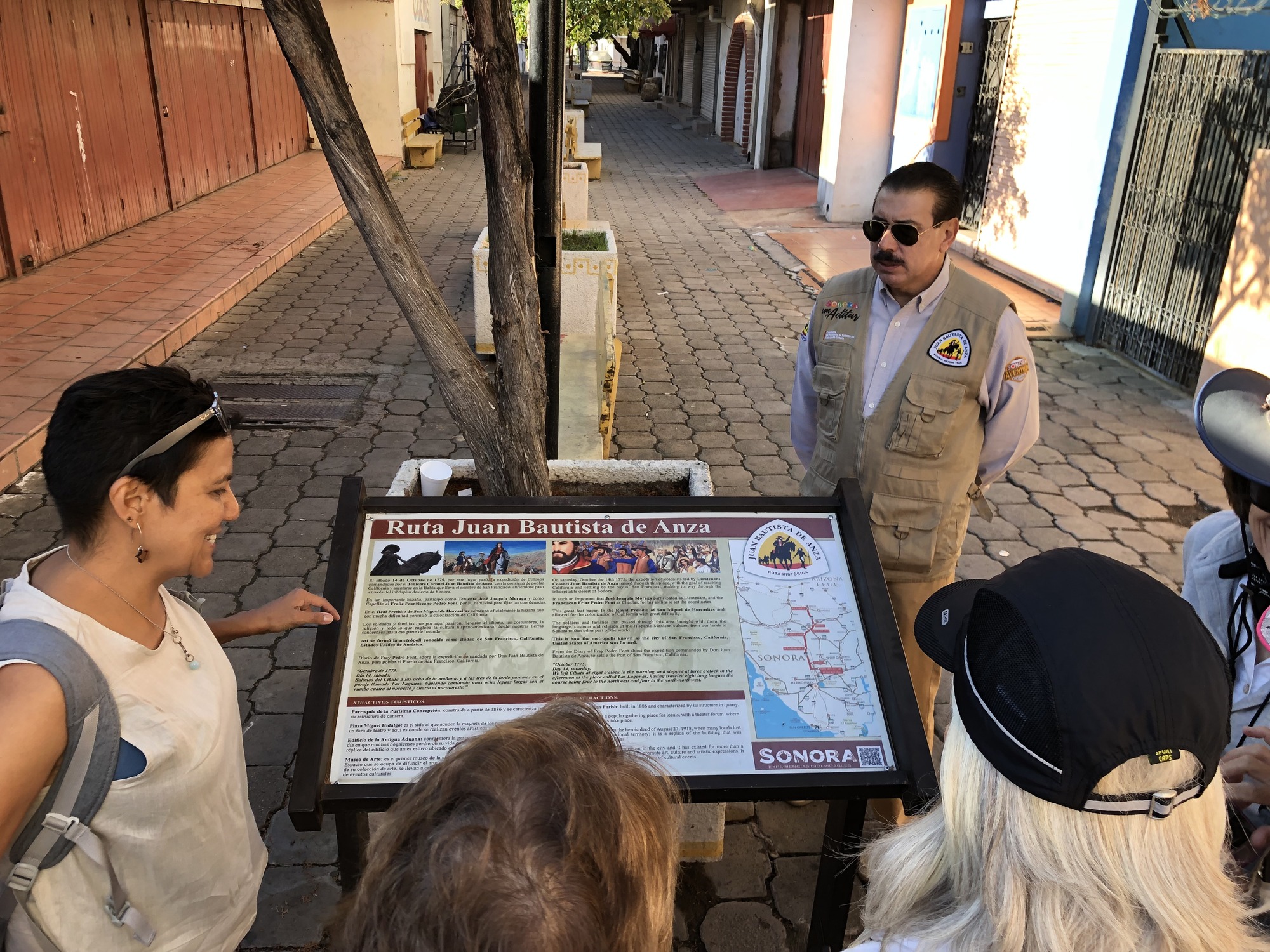 A group of people gather around a Ruta Juan Bautista de Anza interpretive panel