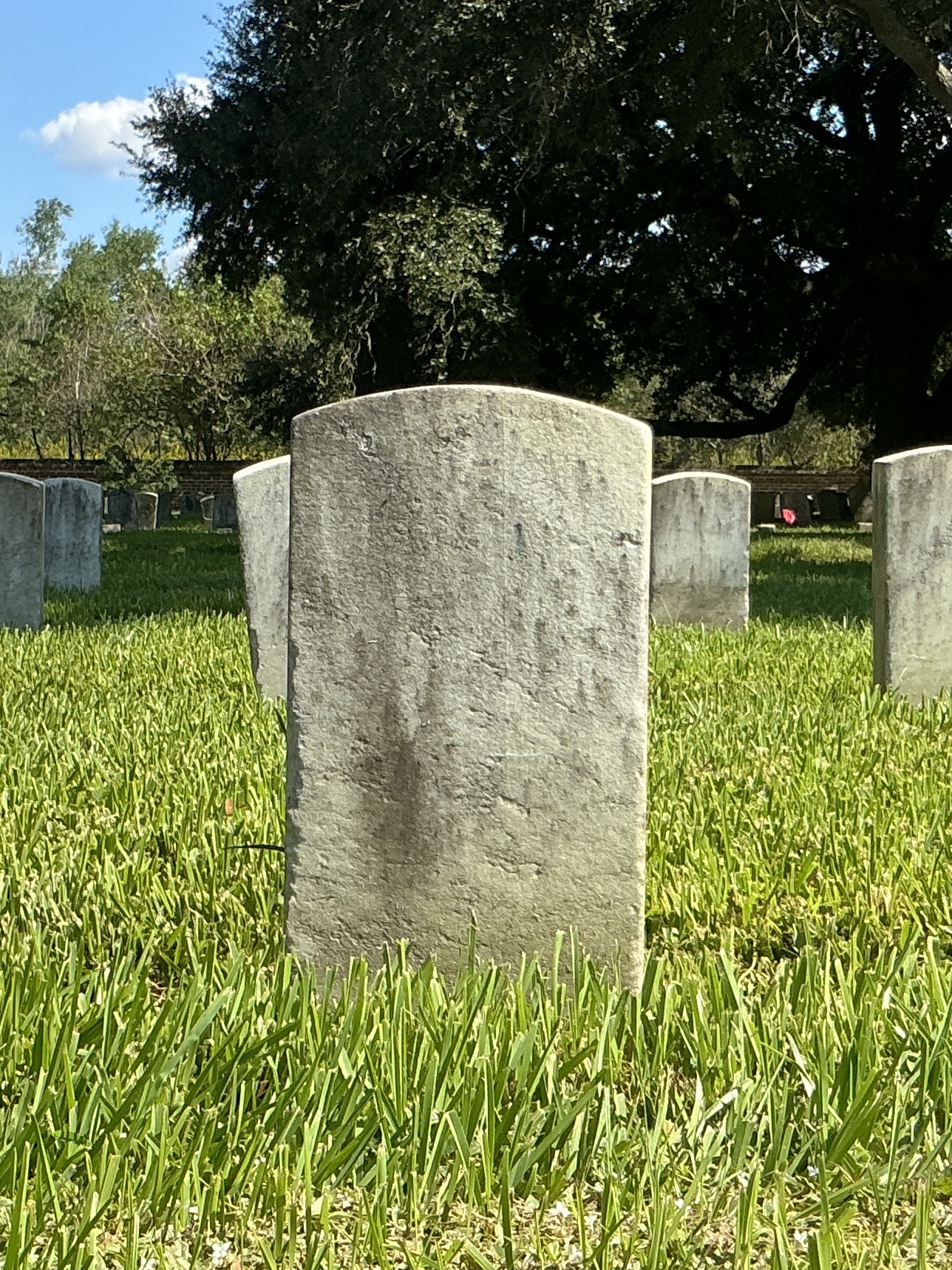 Back of historic upright marble headstone with recessed shield face.