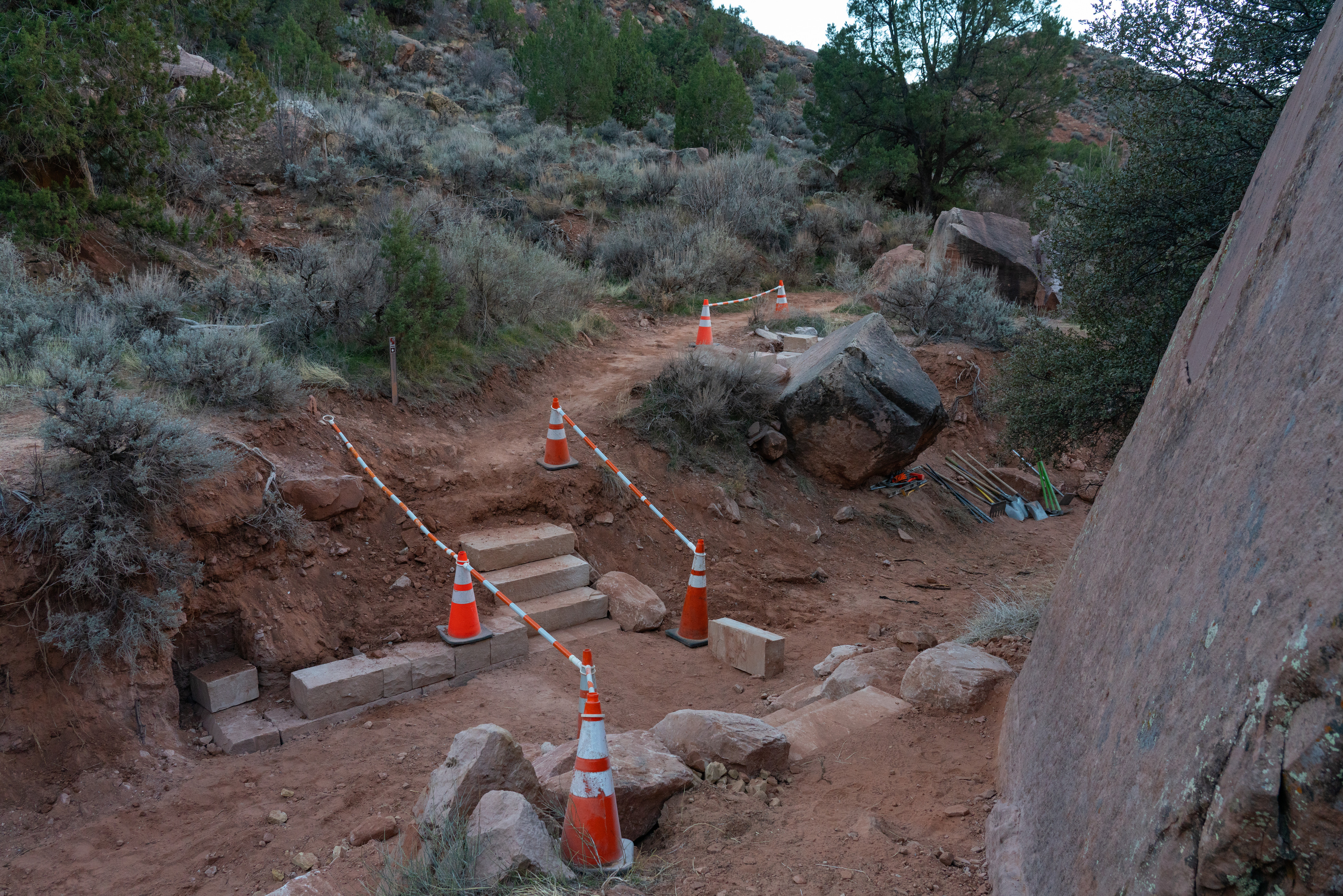 Construction cones on a trail near stairs being installed.