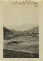 This is an historic black and white photograph from the Scotty's Castle Historic Photograph Collection, Death Valley National Park of Grapevine Canyon looking east from the Scotty's Castle Stables. Fence post and wire mesh on left, wagon frame on right. Circa 1923.