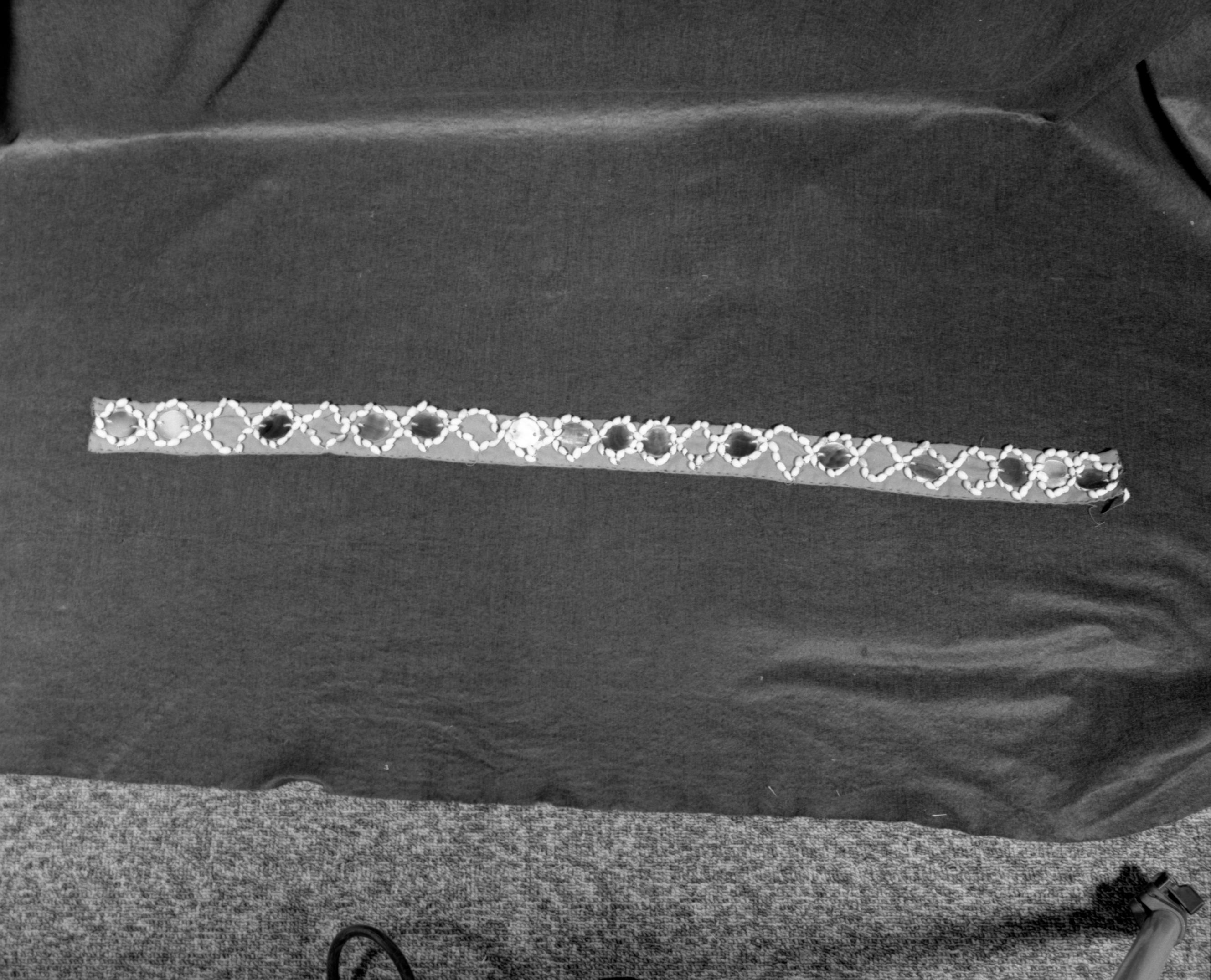 Marie Rozier Collection, Catalog No. 140. Object: Miwok dance belt. Dimensions: 34 1/2". Materials: Red wool, black taffeta (?), olivella shells, commercial mother-of-pearl discs. Collection History: Made by Mrs. Louise Fuentes in 1950s of shells that belonged to her sister Carmelita Ralph, based on styles of dance belts seen in her childhood. Purchased from Mrs. Fuentes. Photographed by Michael Dixon in December 1982. Catalogued by Craig Bates and Barbara Beroza. Yosemite Collections, National Park Service.