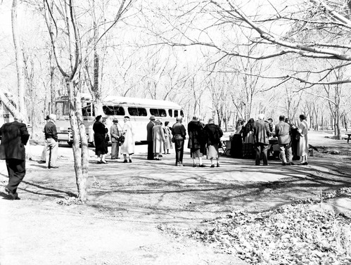 Visitors on Greyhound bus tour standing by picnic table. [Several men and women in traditional Spanish costumes?]