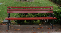 A reddish bench of slat oak wood and cast-iron.