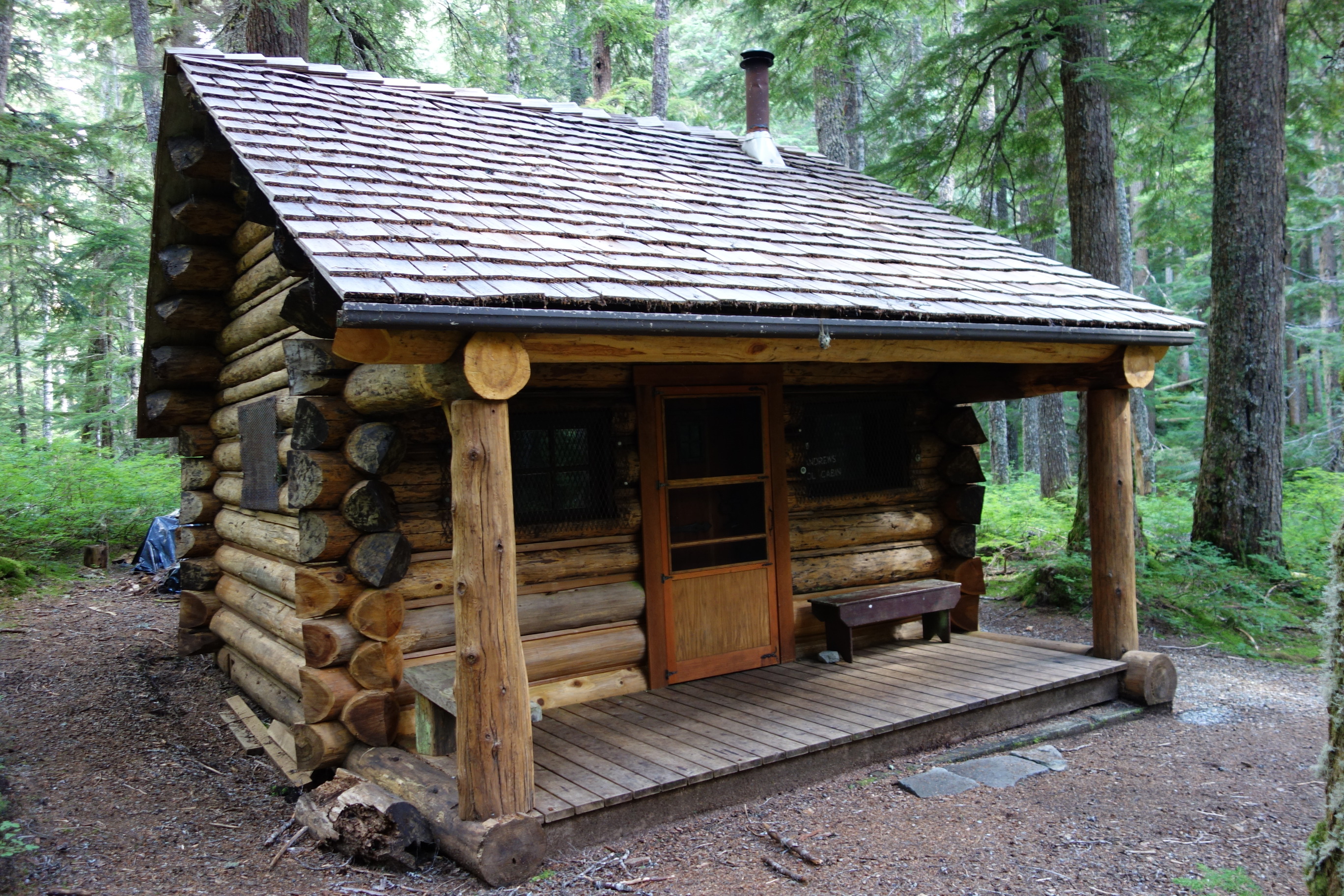 A small log cabin surrounded by forest. 