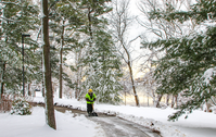 Maintenance worker shoveling snow from a trail near a river