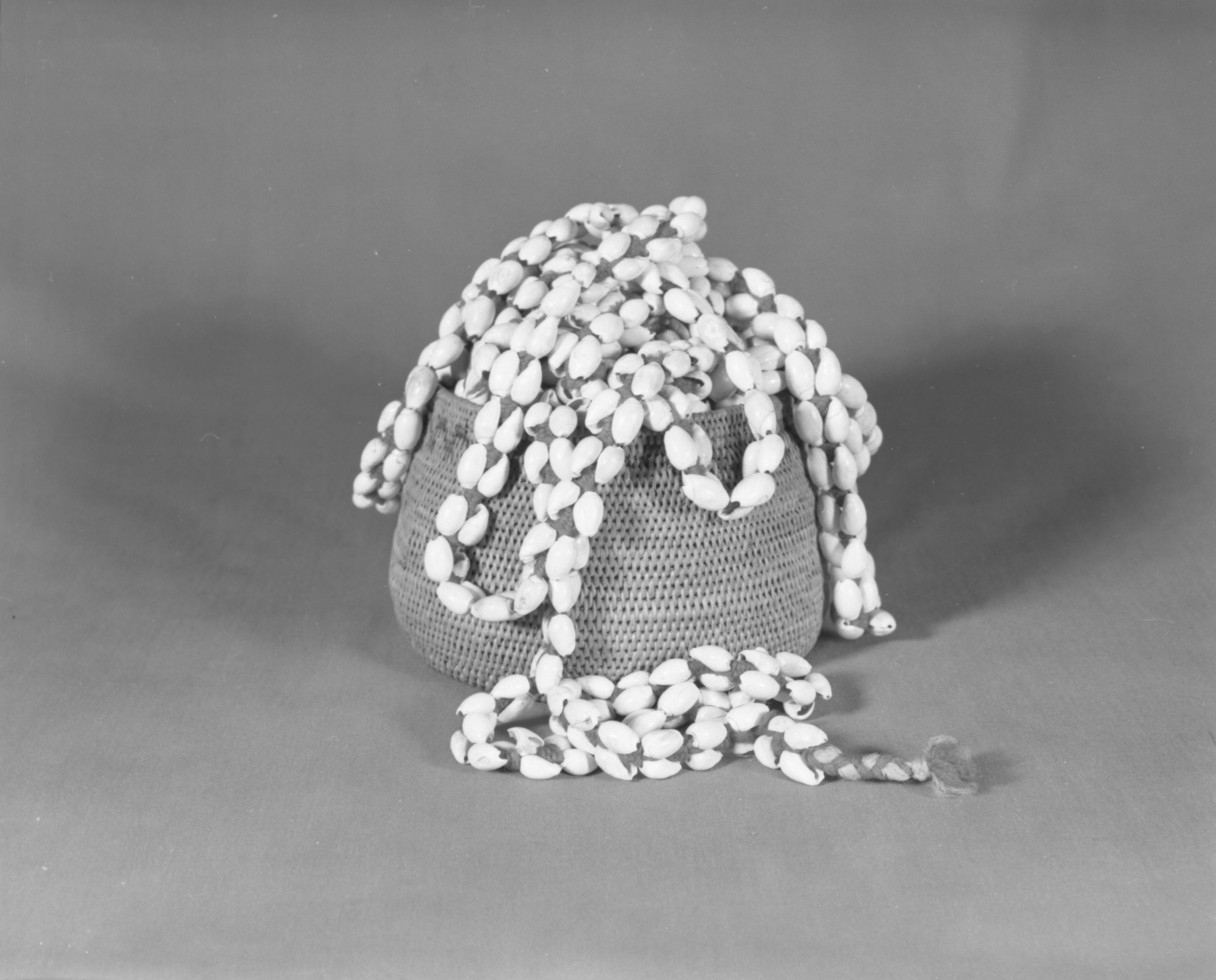 Private Collection. Object: Miwok olive shell rope. Dimensions: 25' 6". Materials: Olivella shells, (baked) average 1/2" (spires removed); strung on commercial cotton cordage. Technology: Woven with usual figure 8 weave using 2 strands of four ply red wool yarn ends terminate in three strand braid with blue grey yarn in addition to red. Collection History: Purchased from Mrs. Mary Longfellow Poncho (Maggie Longfellow Antoninni's mother). Photographed by Michael Dixon. Catalogued by Craig Bates and Barbara Beroza. Yosemite Collections, National Park Service.
