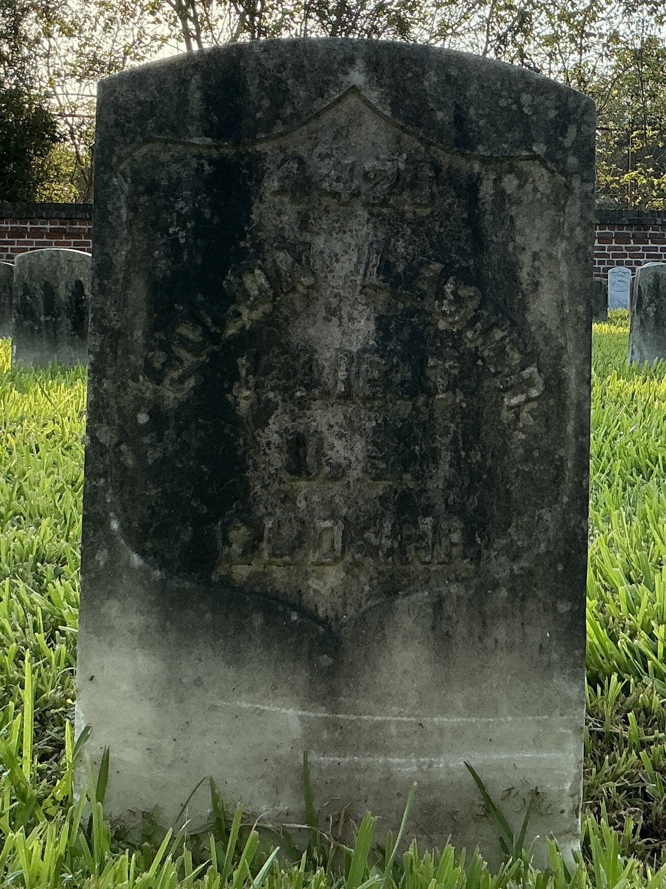 Front of historic upright marble headstone with recessed shield face.