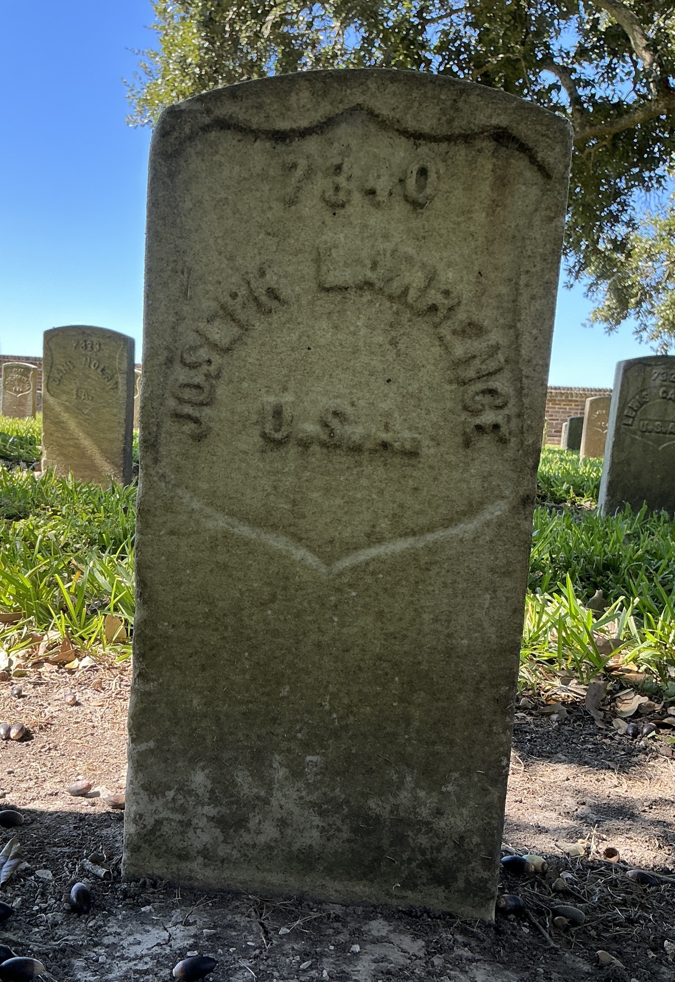 Front of historic upright marble headstone with recessed shield face.