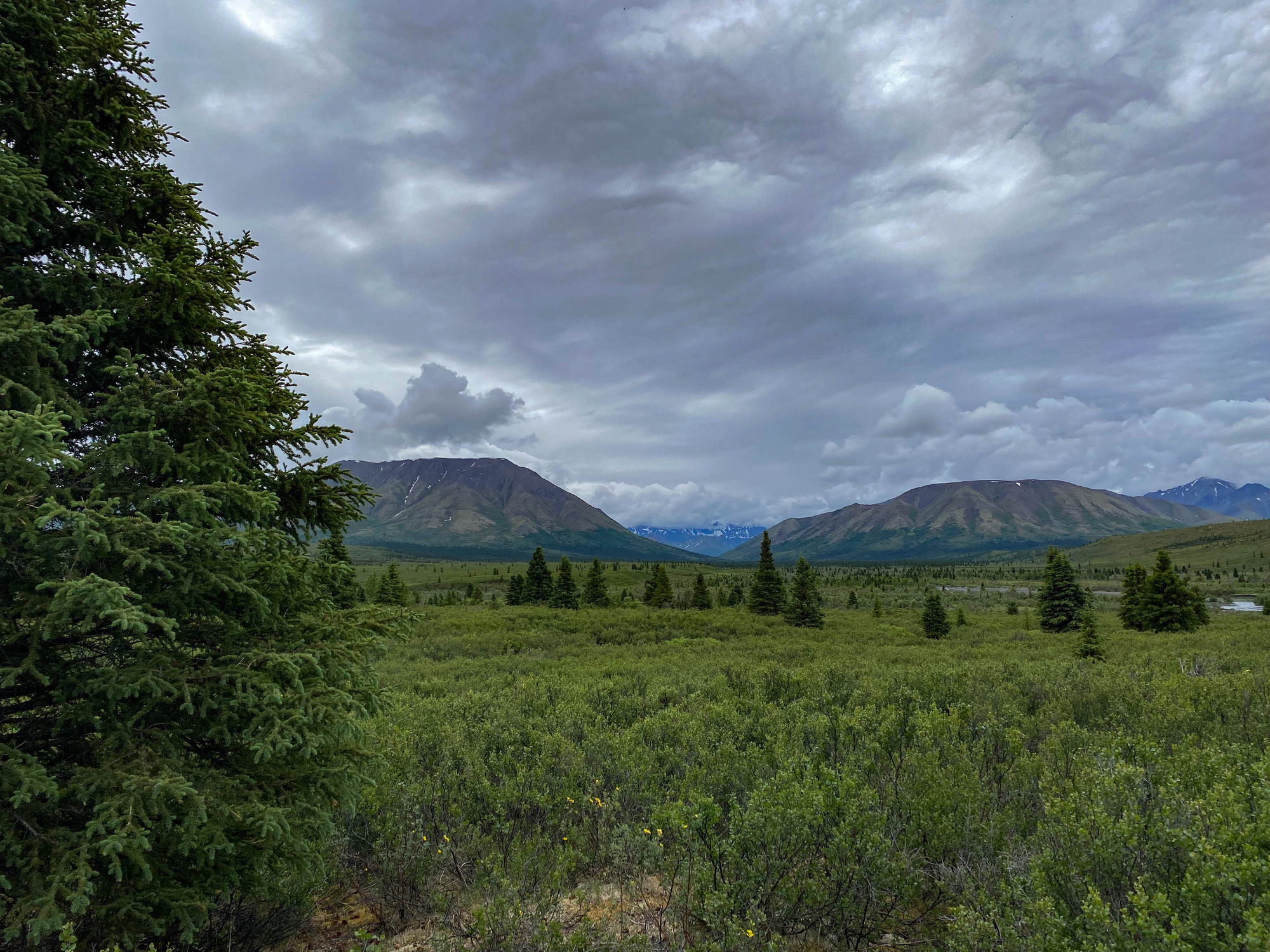 A gap in the mountains revealing more mountains in the distance under heavy cloud coverage 
