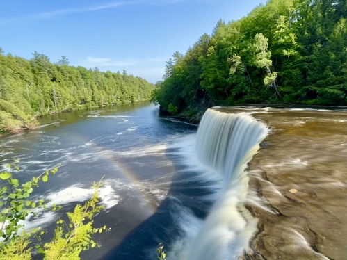 A long exposure of a rainbow next to a wide waterfall