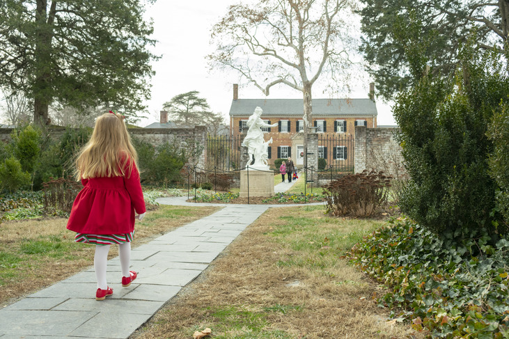 A girl in a red dress in front of Chatham Manor.