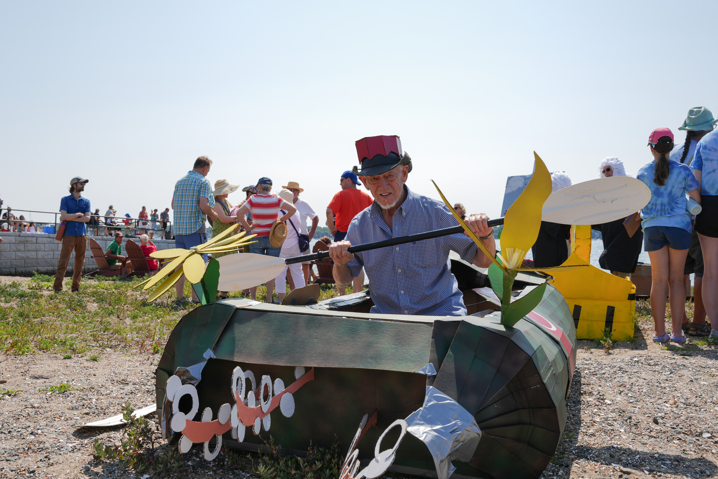 A man sits in a decorated cardboard boat.