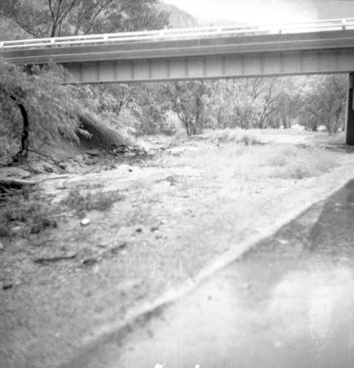 Flood water raging under bridge and overflowing from an open irrigation gate. Down pour of 1.38-inches in one hour.