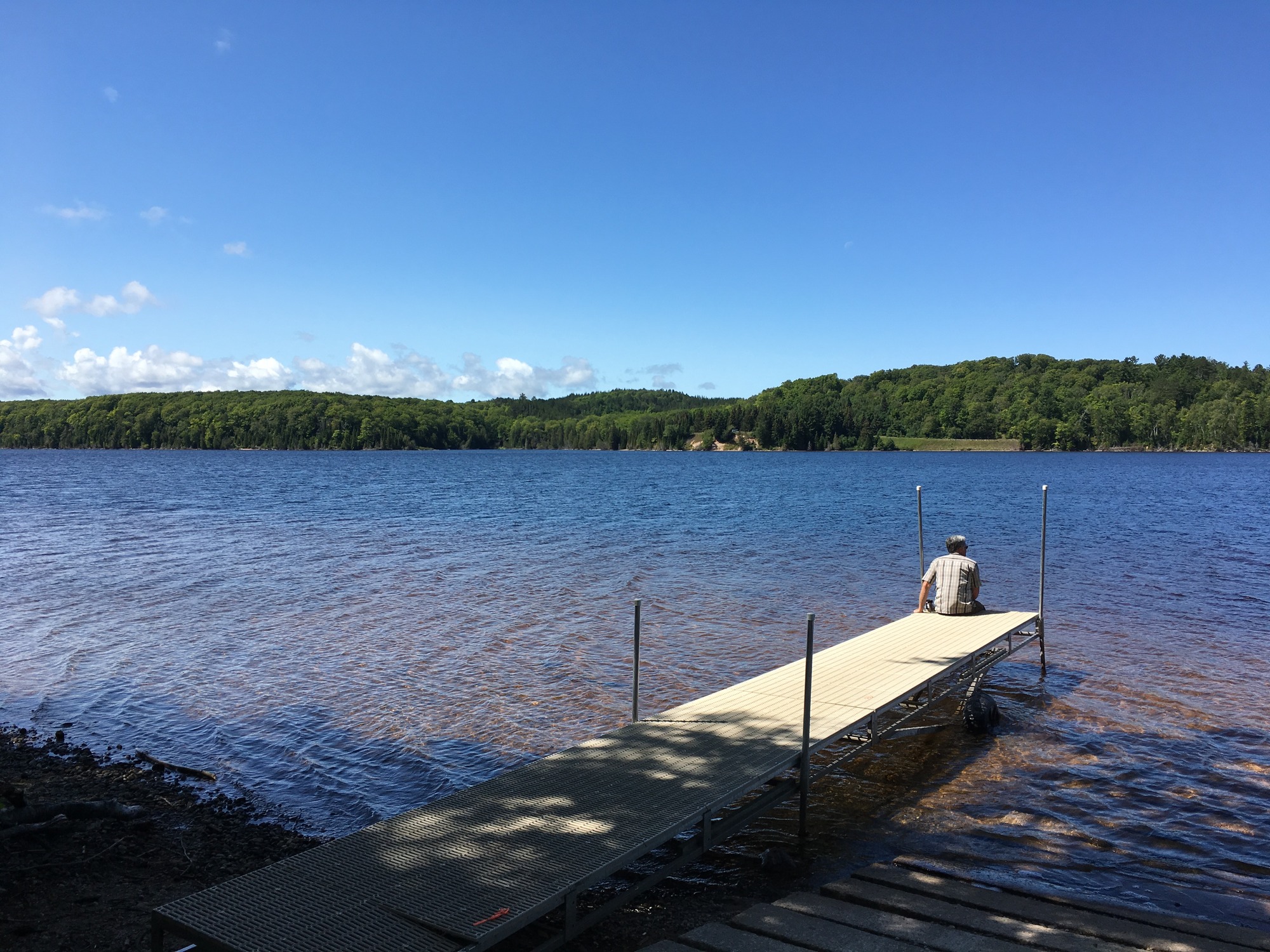 Portable dock with person sitting at the end on Grand Sable Lake