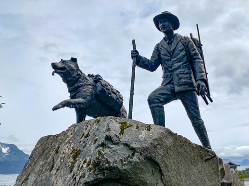 Statue of a hiker with a dog on a stone base