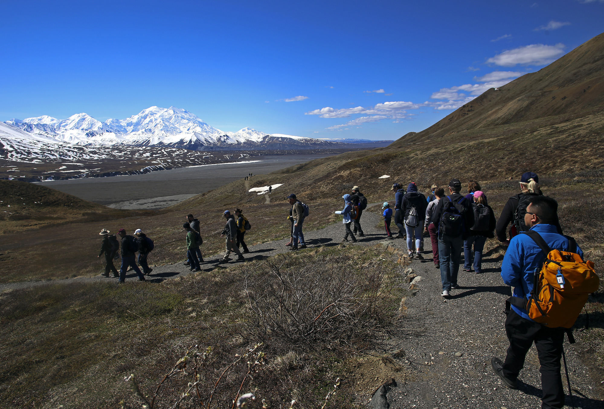 a park ranger leading about twenty people on a trail walk