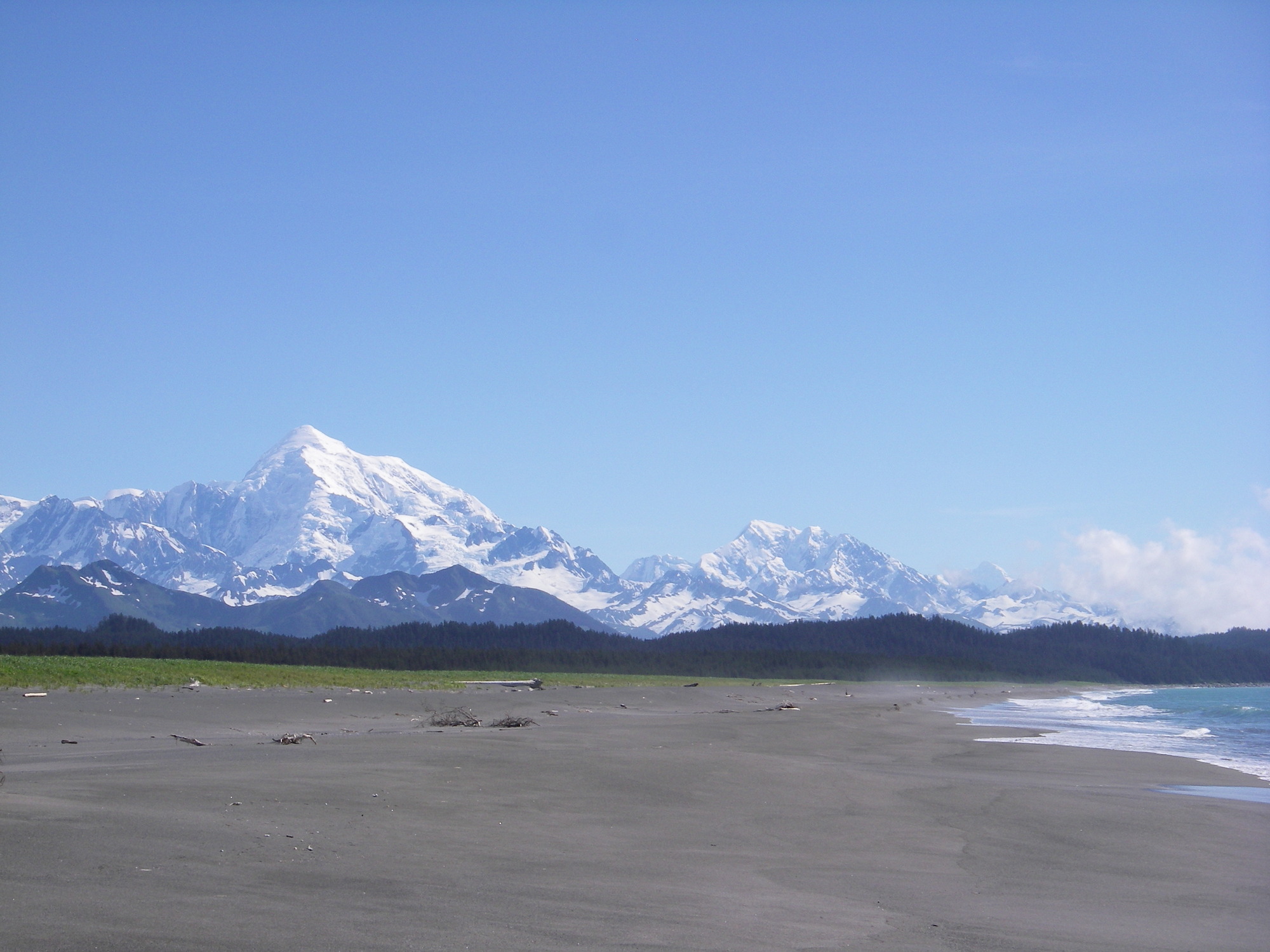 Open beach with white peaked mountains in the background