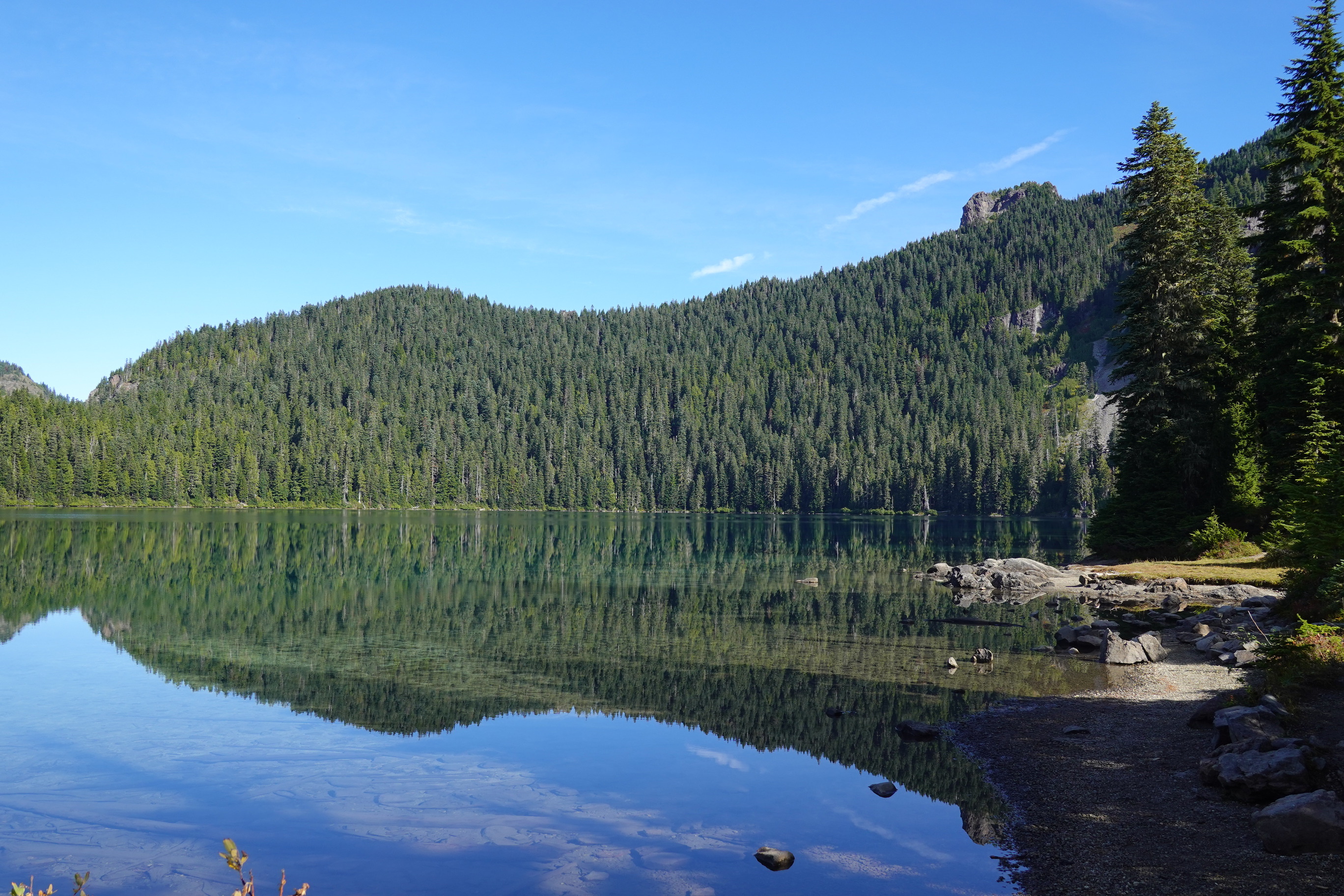 Forested hillsides reflect in the still waters of a mountain lake. 