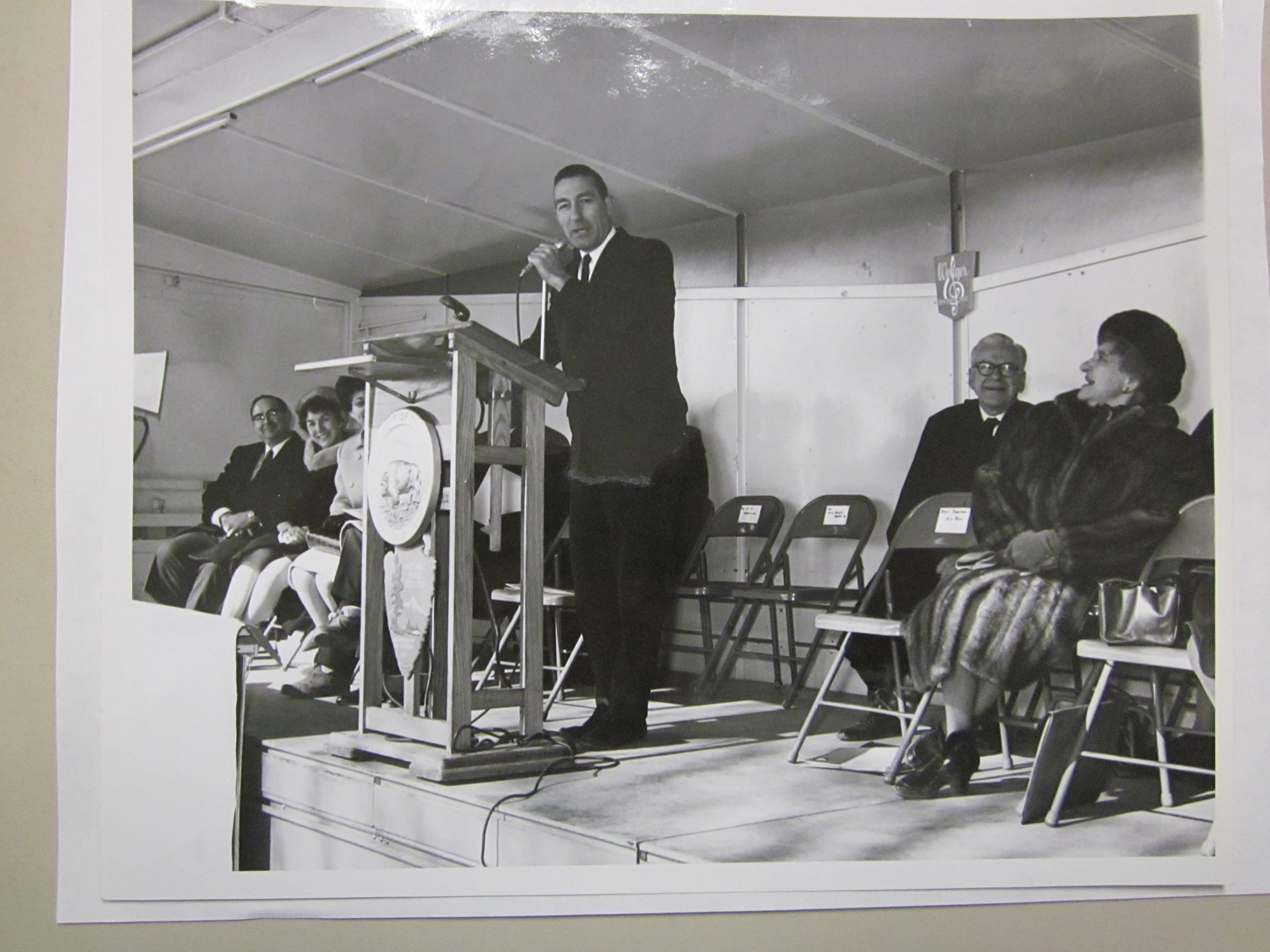 Interior Secretary Udell standing at the podium.  Two people seated to the right, and three on his left.