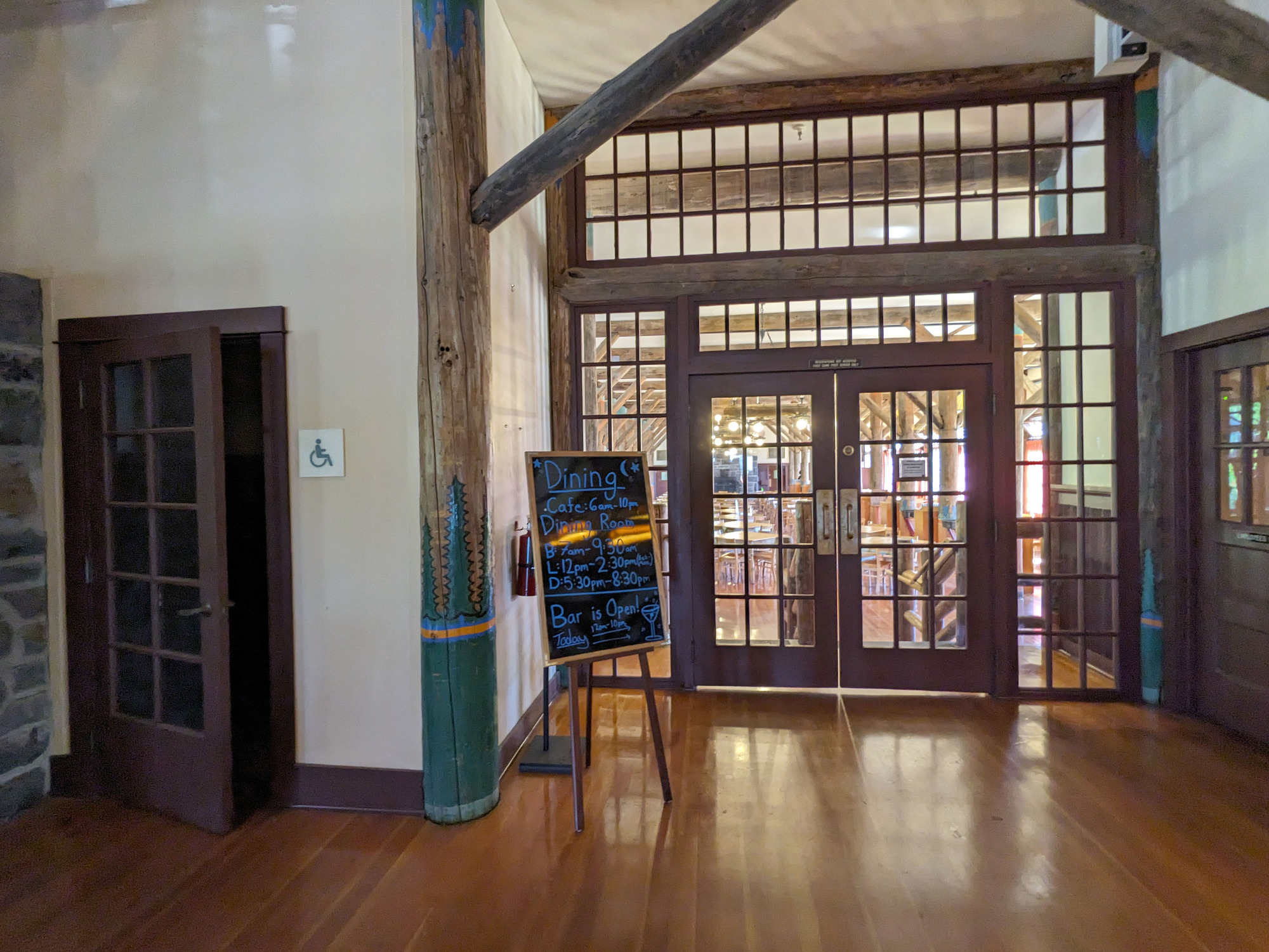 A large doorway with windowed double doors leads to a dining room. A single door on the left is ajar, leading to the accessible entrance.