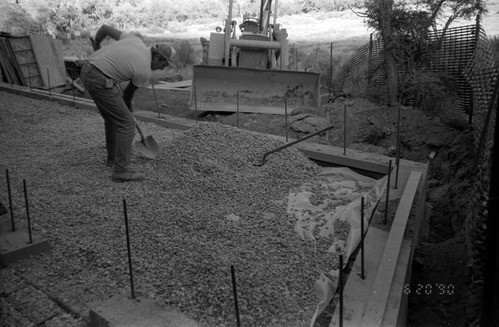 Worker shoveling gravel during at construction of headquarters addition.