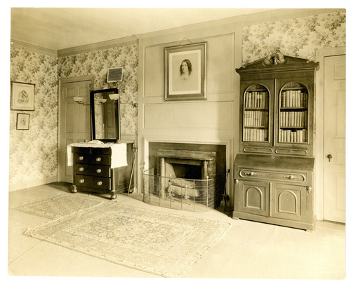 Black and white photograph of fireplace with a portrait above.