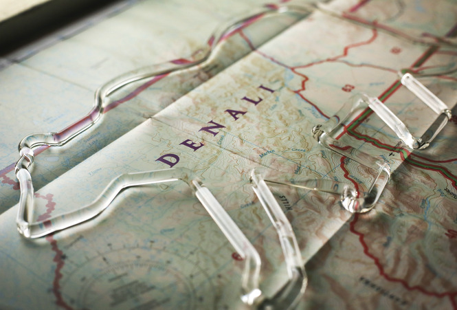 a glass bear resting on a map of Denali