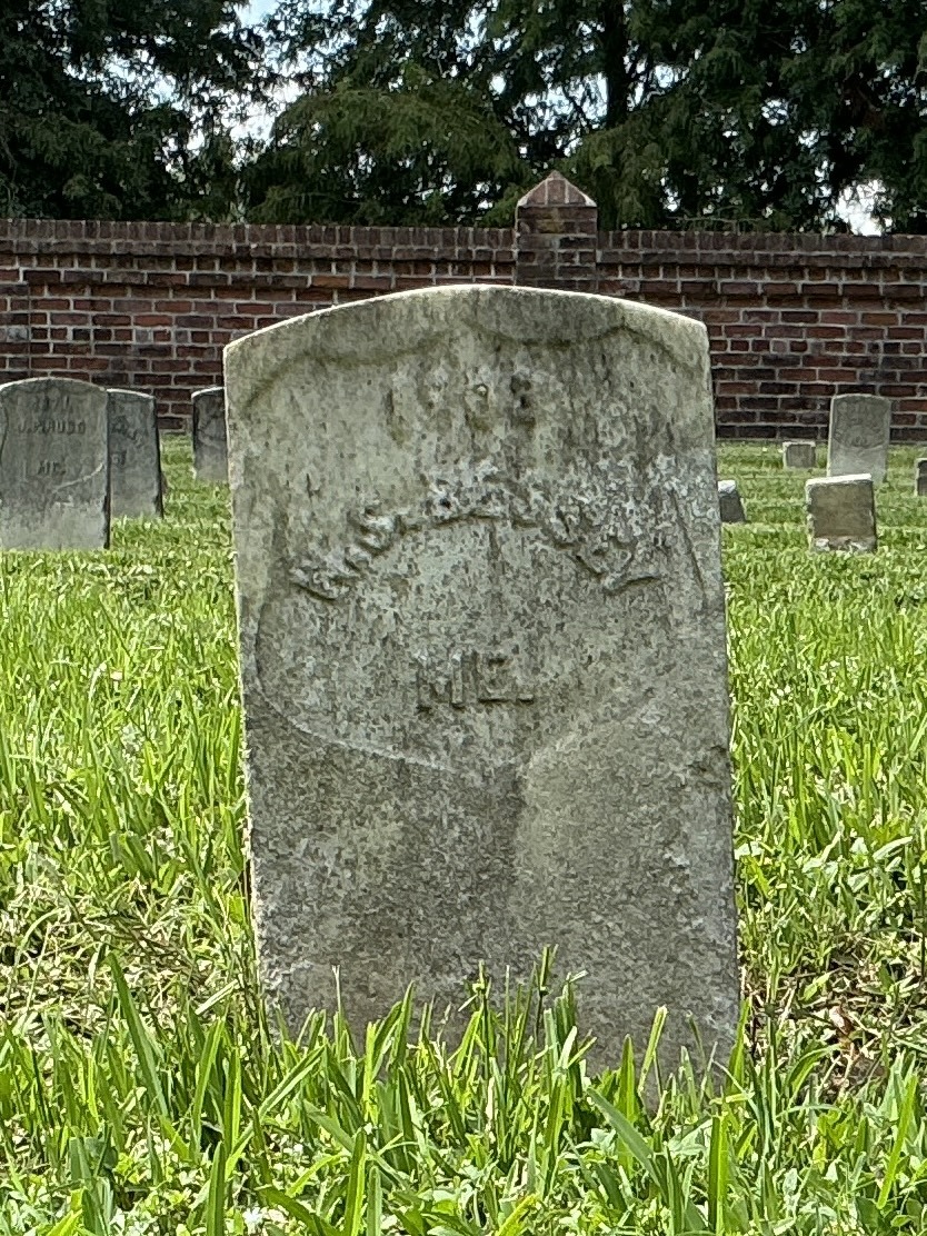 Front of historic upright marble headstone with recessed shield face.