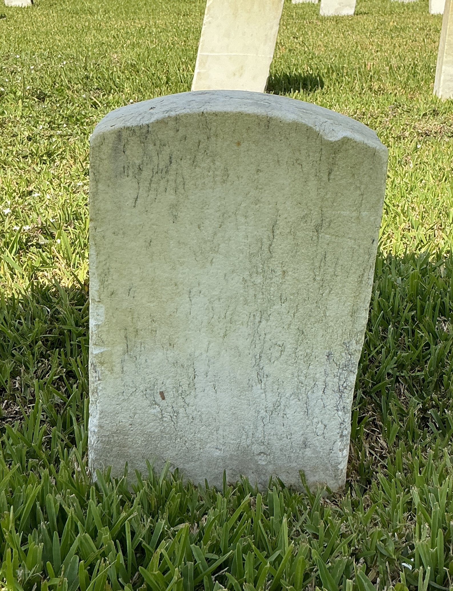 Back of historic upright marble headstone with recessed shield face.