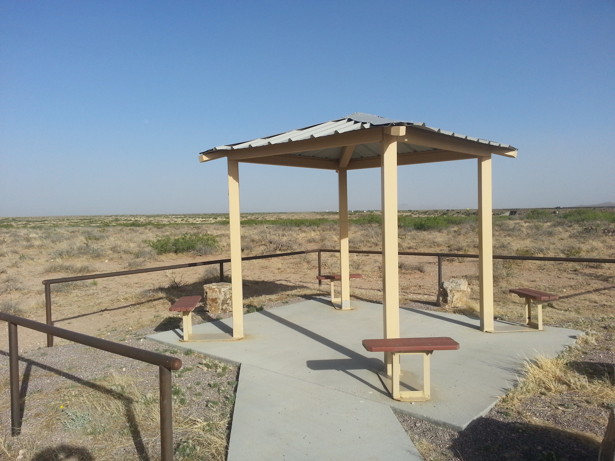 A gazebo with benches in the middle of the desert.