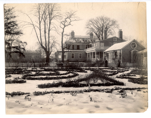 Formal garden in snow, only the outline of bushes visible.