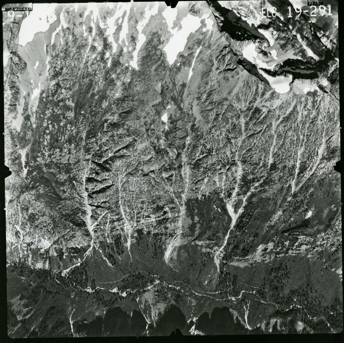 Black and white aerial photograph of glaciated mountain peaks and valleys.