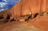 Photograph of slickrock in Glen Canyon National Recreation Area. The cliff is orange-and brown sandstone with prominent cross beds.