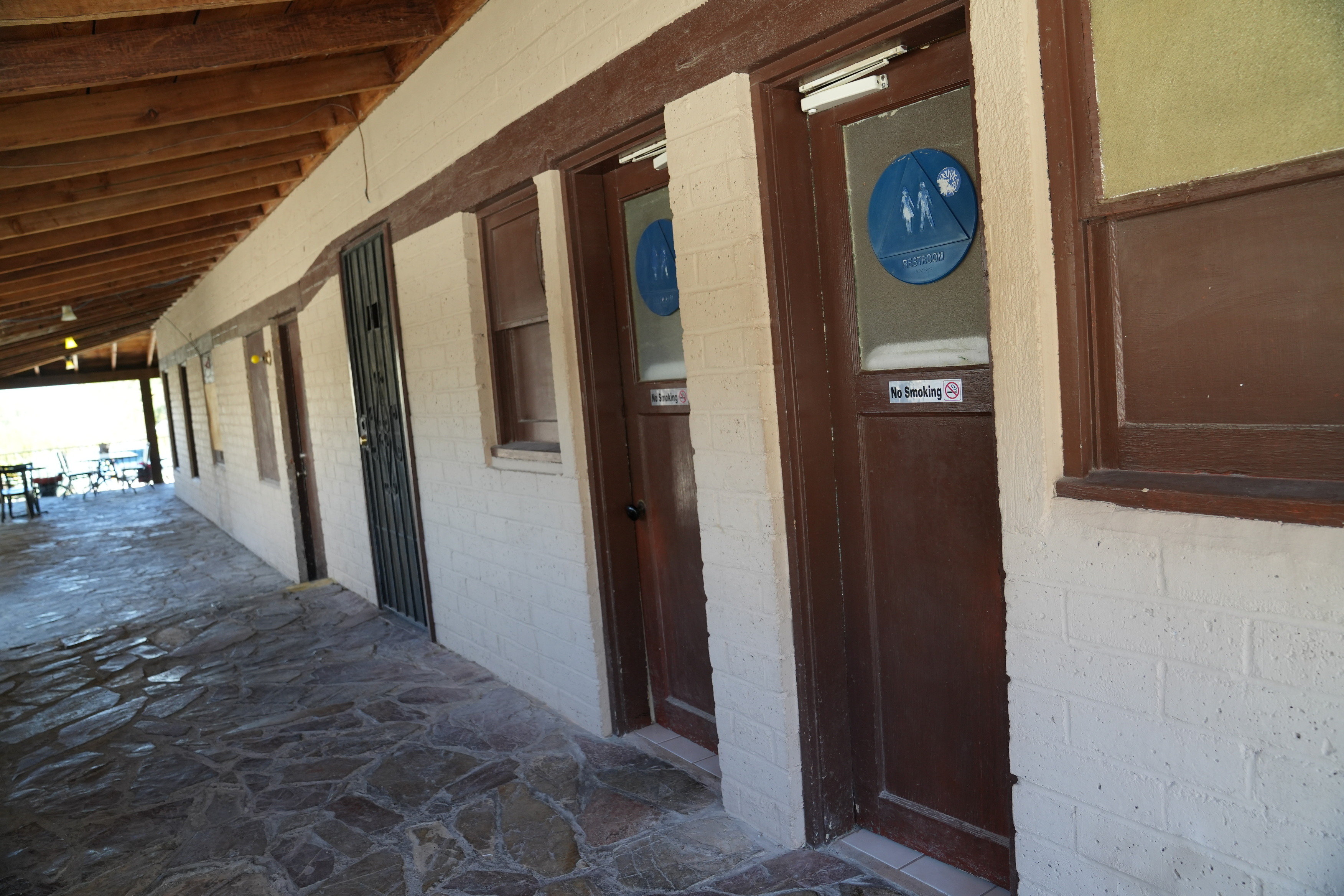 Panamint Springs Bar and Grill bathrooms. Old-style narrow wooden doorway that transitions from concrete to tile flooring.