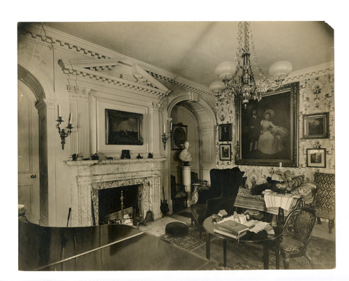 19th century parlor, crowded with seating, elaborate Georgian molding above fireplace.