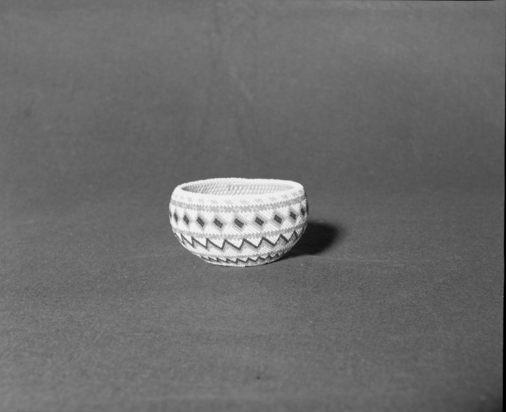 Mrs. Donald Segerstrom Collection. Object: Paiute or Washoe beaded basket. Dimensions: 5 x 2 1/2". Materials: Split willow shoots, glass beads. Technology: Interlocking stitch, oval start, single bead peyote stitch. Photographed by Michael Dixon. Catalogued by Craig Bates and Barbara Beroza. Yosemite Collections, National Park Service. 1/83.