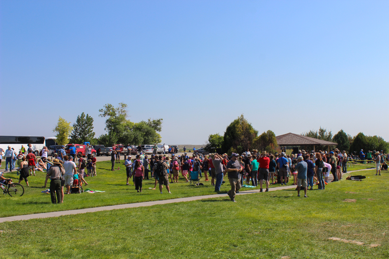 Large crowd of visitors scattered across a patio and grassy areas.