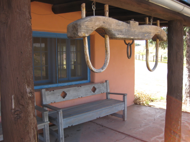 Brown cattle yoke, gray bench, and blue windows on the porch of the Forked Lightning Ranch